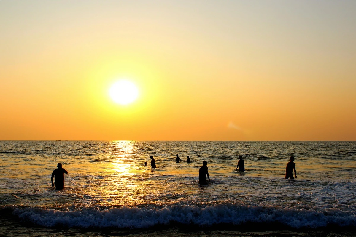 A lively beach in Goa with beach shacks and people enjoying the sunset